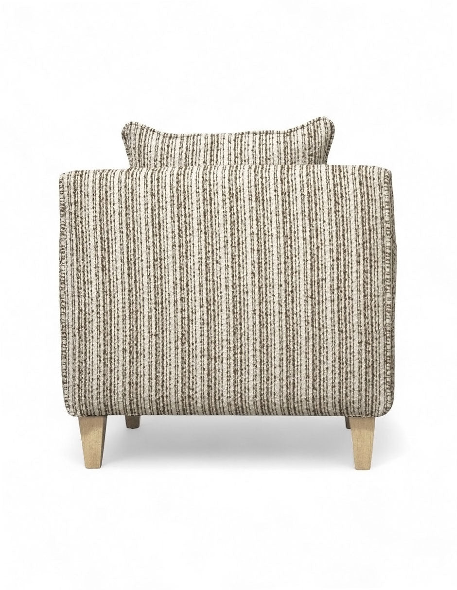 Vista trasera sillón beige de tela texturizada con diseño moderno, cojín de respaldo suelto, cojín decorativo rectangular y patas de madera natural