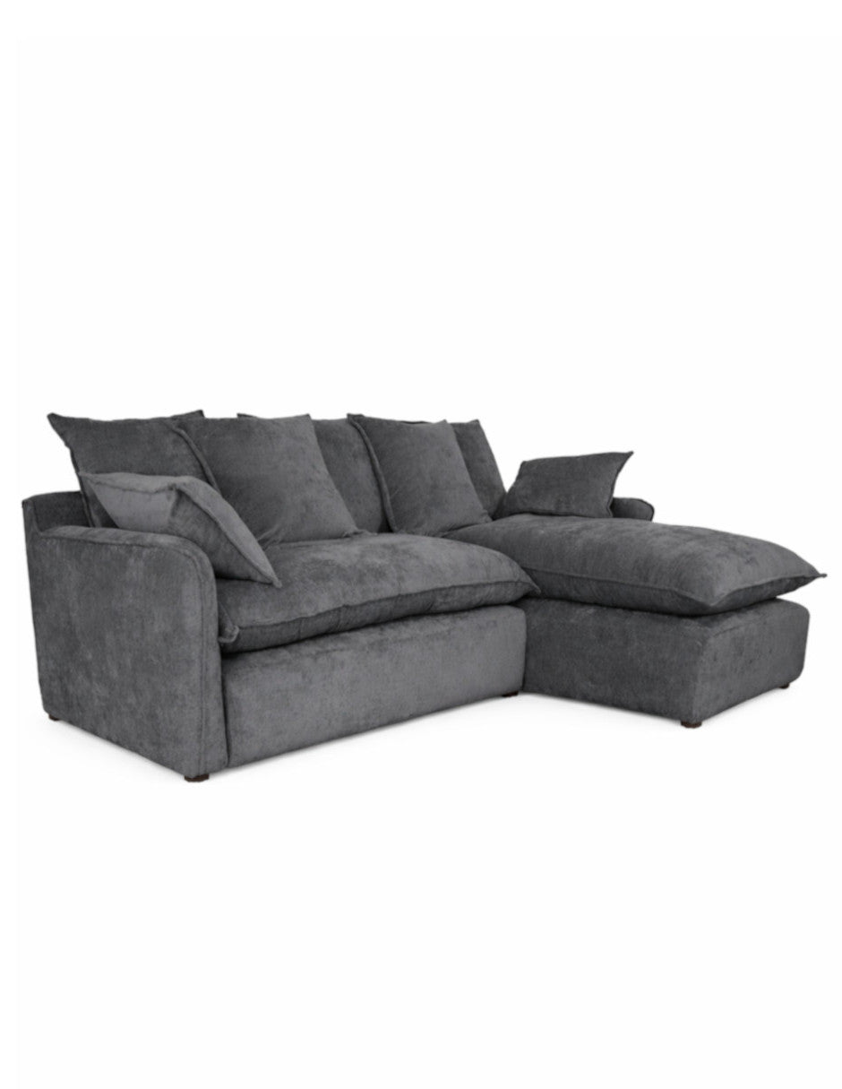 Vista 3/4 sofá en L gris oscuro moderno con chaise derecho, cojines amplios tipo almohadón 