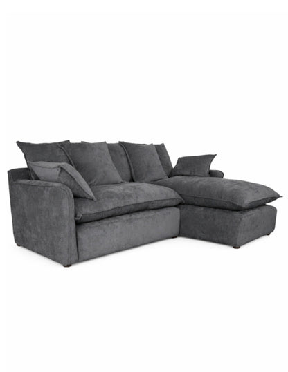 Vista 3/4 sofá en L gris oscuro moderno con chaise derecho, cojines amplios tipo almohadón 