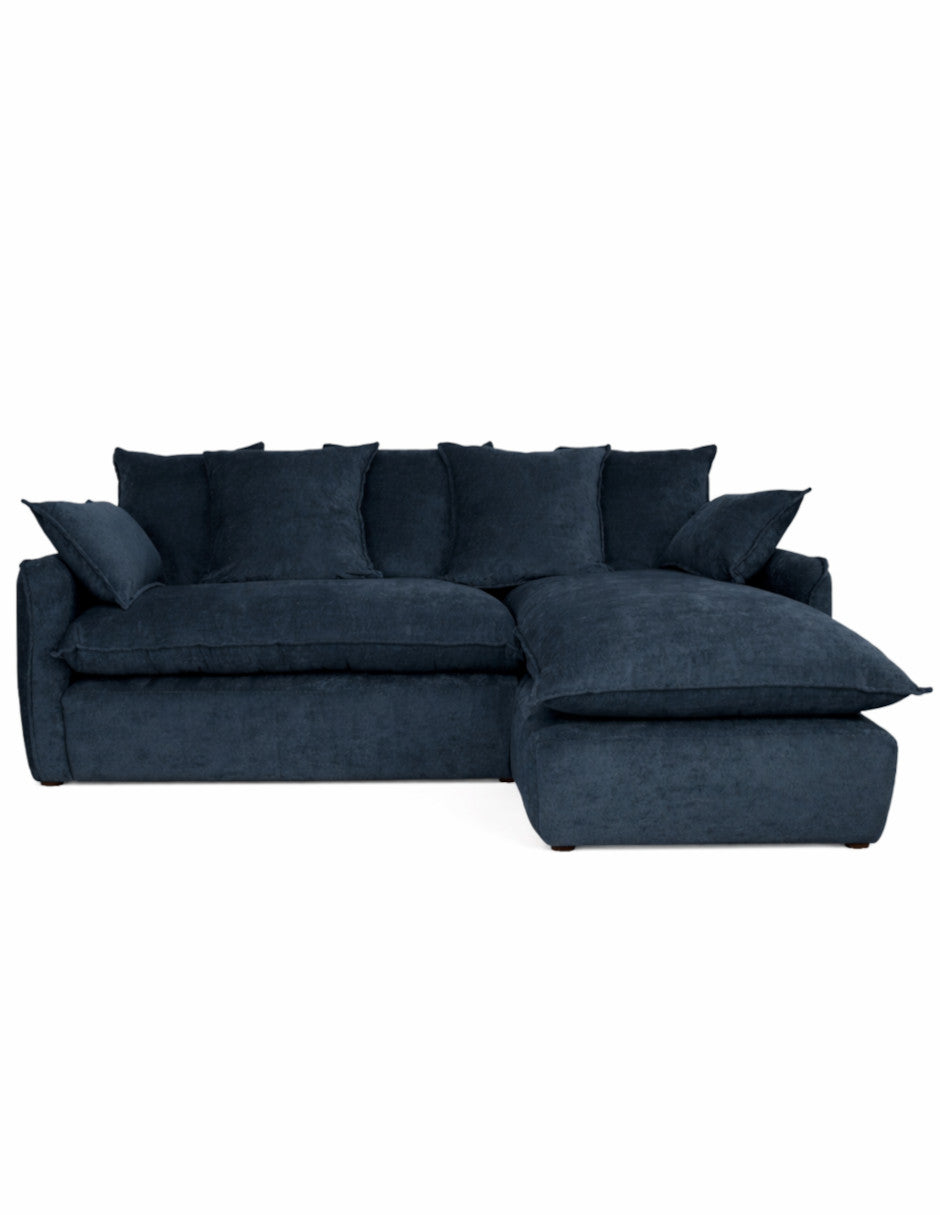 Vista frontal sofá en L azul oscuro moderno con chaise derecho, cojines amplios tipo almohadón 