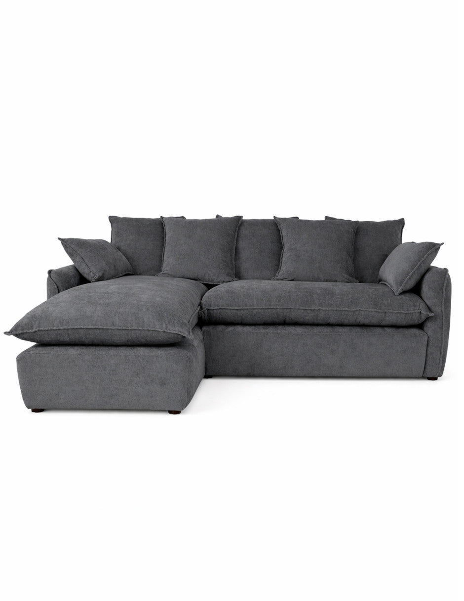 Vista frontal sofá en L gris oscuro moderno con chaise izquierdo , cojines amplios tipo almohadón 