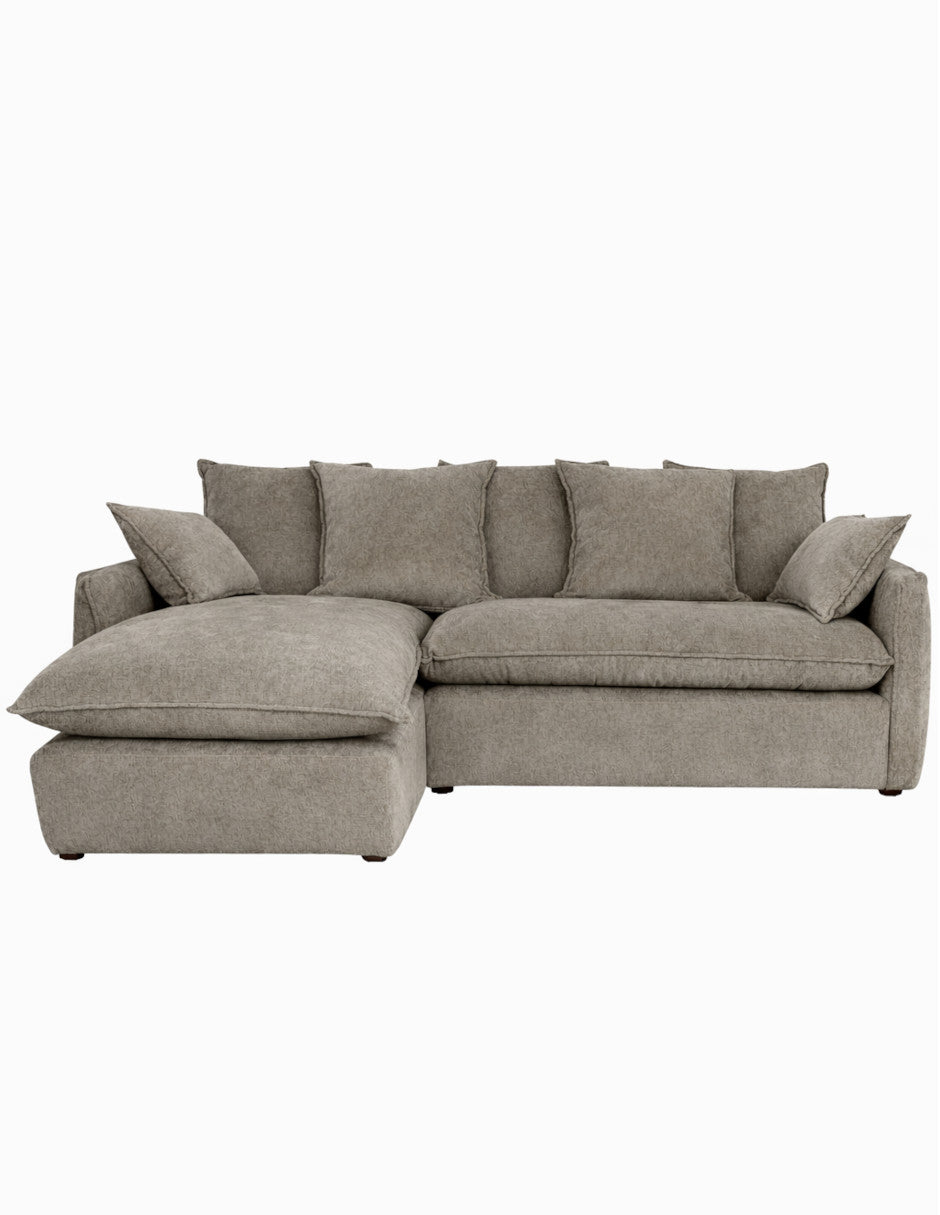 Vista frontal sofá en L taupe moderno con chaise izquierdo, cojines amplios tipo almohadón 