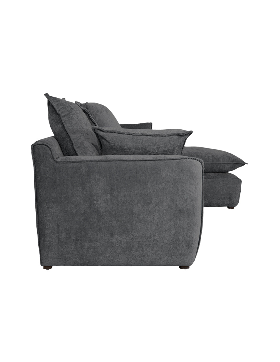 Vista lateral sofá en L gris oscuro moderno con chaise derecho, cojines amplios tipo almohadón 