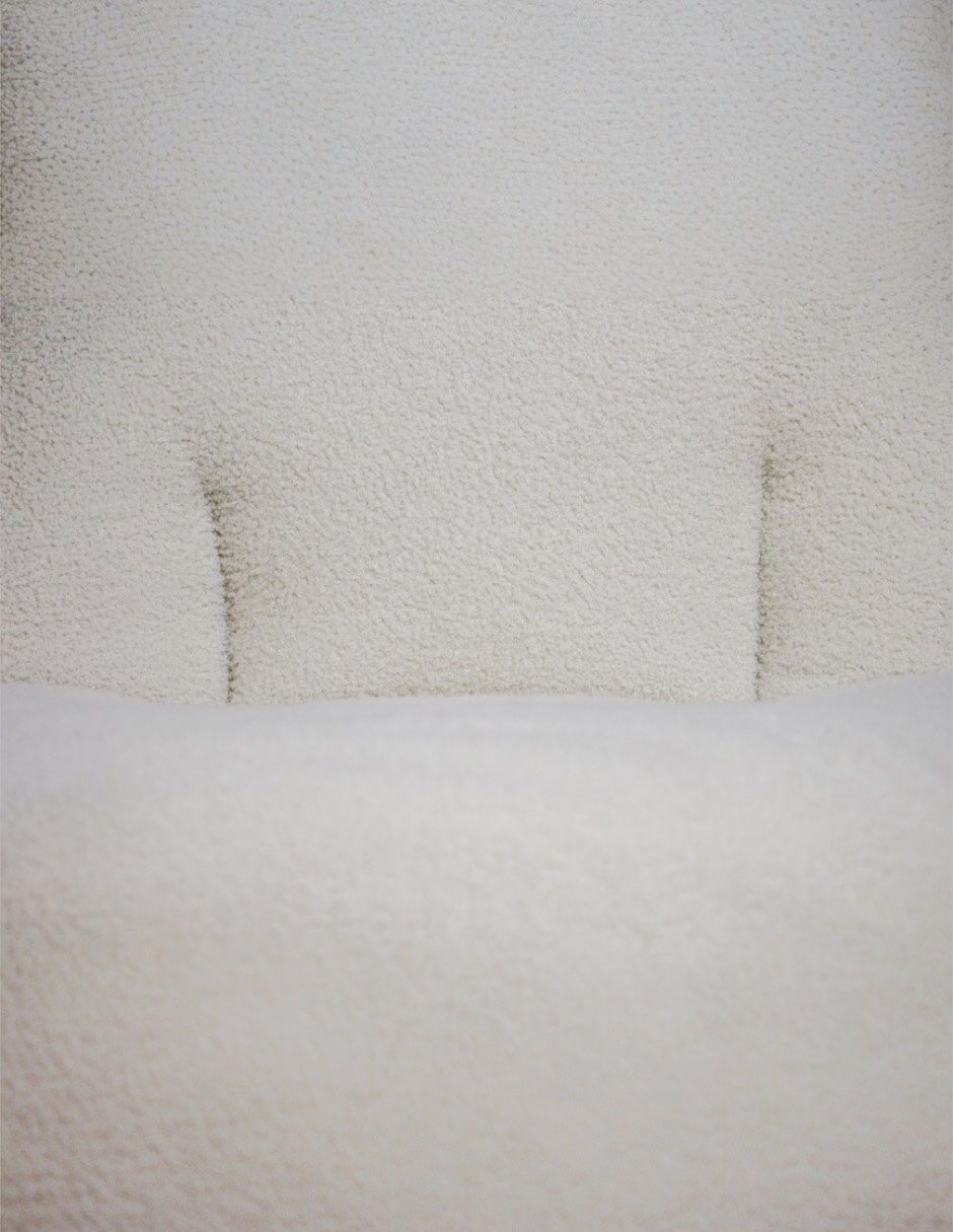 Detalle de respaldo acolchado en sillón blanco tela bouclé
